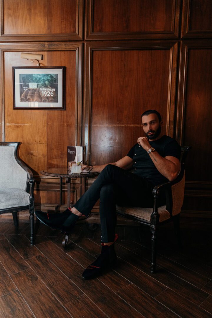 A man in black dress and black loafer sitting on the chair