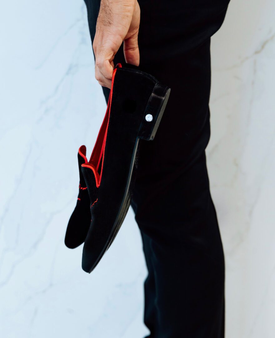 A man holding zeusori black color velvet shoes in his hand