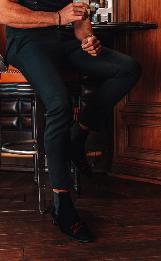 A closeup of the black color velvet loafers with red color logo