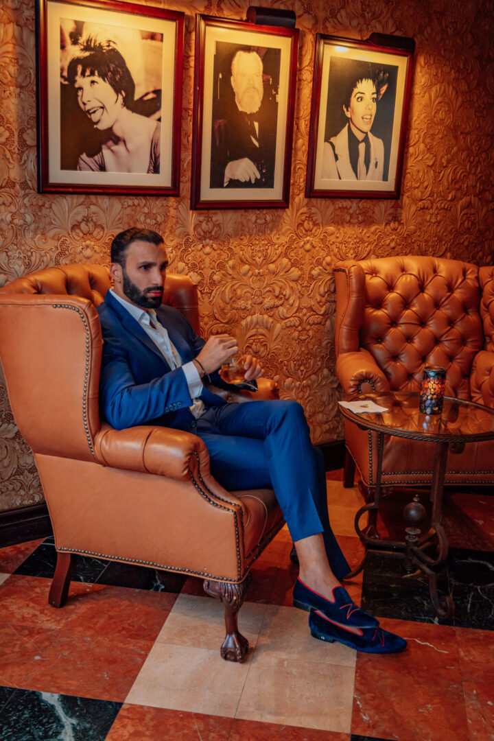 A man in blue color loafers sitting and holding the glass